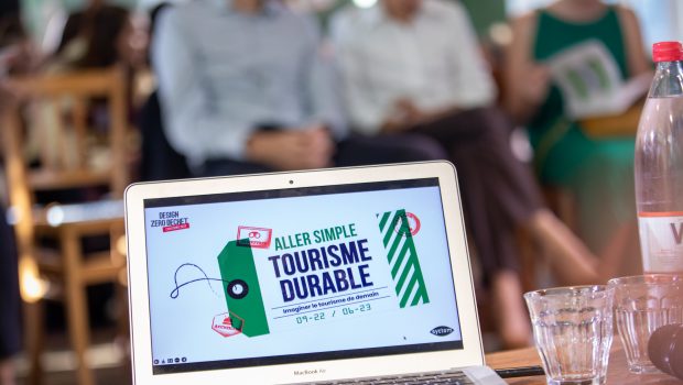 Photo d'un écran d'ordinateur présentant le visuel de l'édition Design Zéro Déchet 2023, "Aller simple vers un tourisme durable", devant une foule assise.